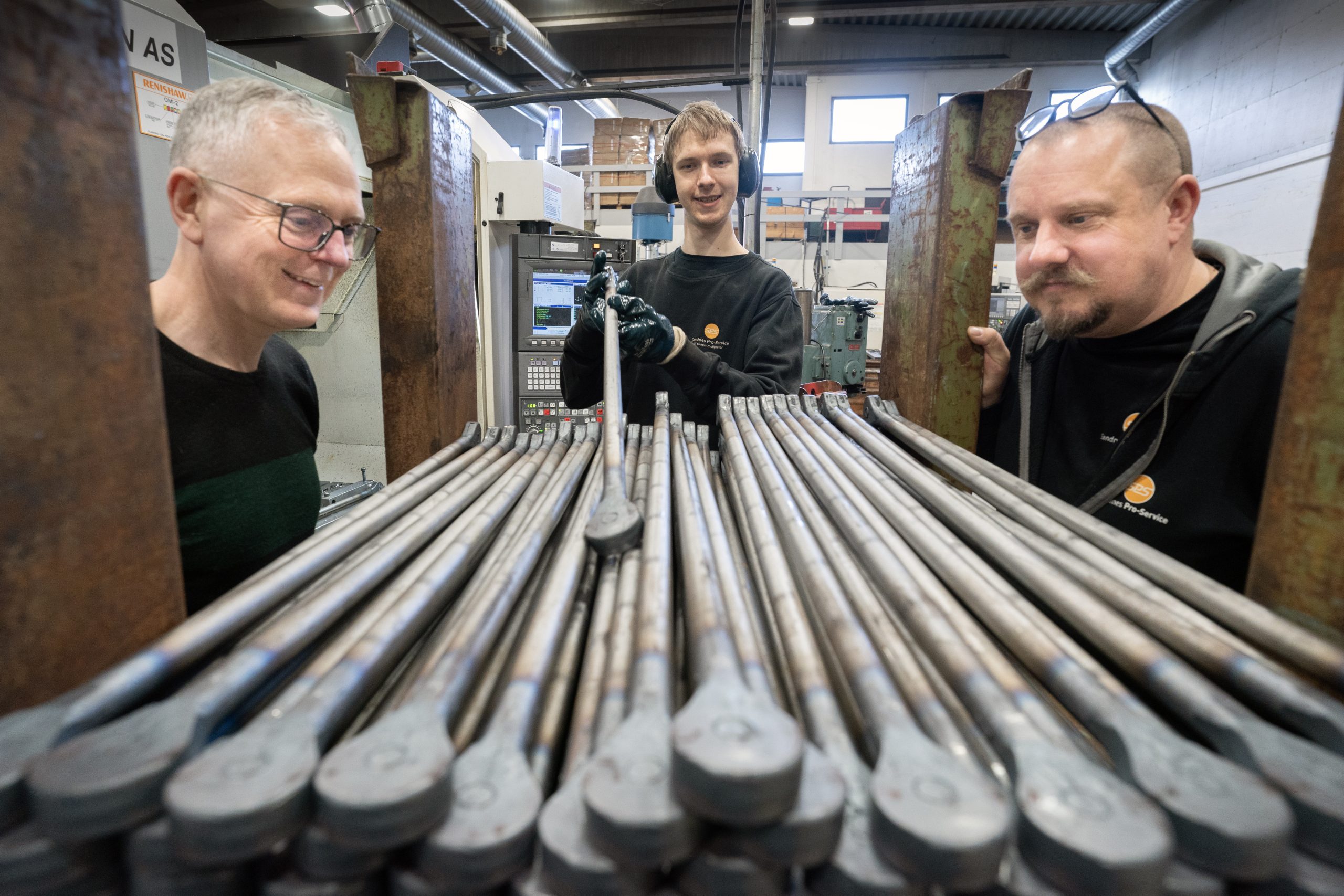 Tre menn på mekanisk verksted.